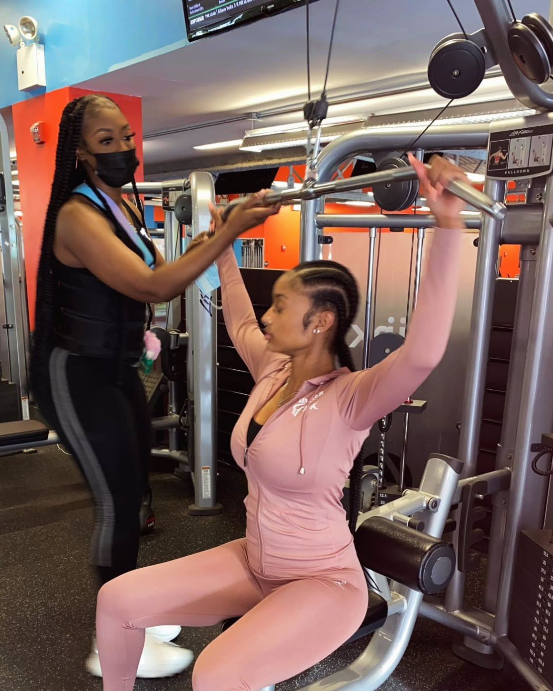 Ally coaching a client on the lat pulldown